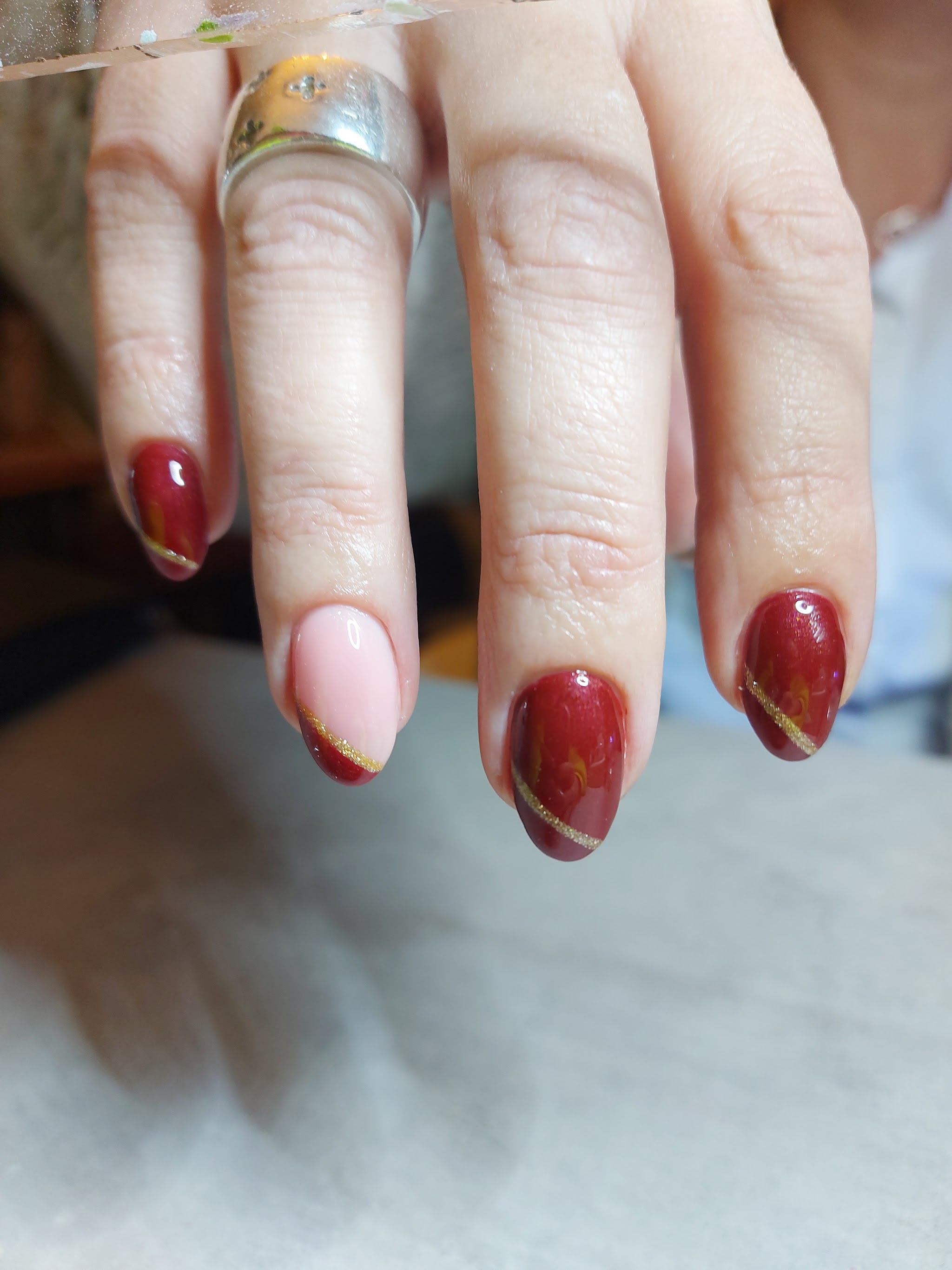 Dieprode nagels met een gouden streep en een lichtroze accentnagel